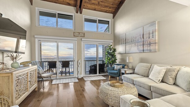 Un salón espacioso con techo alto, ventanas grandes y balcón con vistas al océano.
