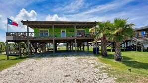 A two-story building with a green facade and a balcony. - Spacious beach bungalow 1 block from the ocean, 4 bedrooms (Freeport)