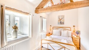 Une chambre à coucher avec un lit, une fenêtre donnant sur un beau paysage, un radiateur et une poutre en bois au plafond.