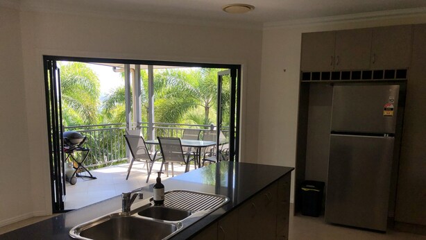 Eine moderne Küche mit Edelstahlkühlschrank, einer Spüle und einem Balkon mit Gartenmöbeln.