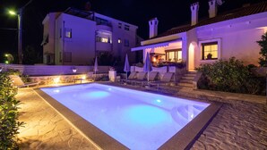 Une piscine bordée de pierres, avec des chaises longues et des parasols.