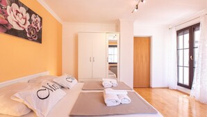Une chambre d’hôtel comprenant un lit, des oreillers, des serviettes, un tableau, une armoire et une porte donnant sur une autre pièce.