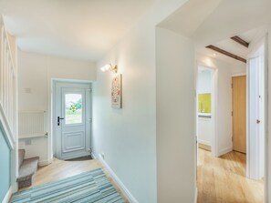 A hallway with a light blue door, a wall-mounted light fixture, and a blue striped rug.