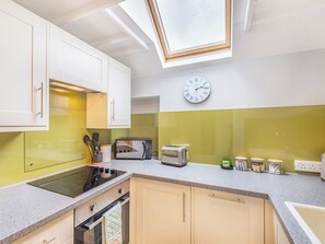 Una cucina moderna con un lucernario, un forno a microonde, un tostapane e una sveglia appesa al muro.