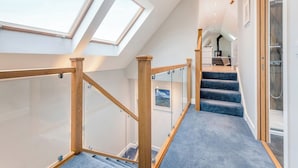 Un escalier moderne avec des rampes en verre, une verrière et une vue sur l’étage supérieur.