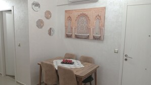Ein Essbereich mit einem für vier Personen gedeckten Tisch, umgeben von Stühlen. Darüber hängt eine dekorative Wanddekoration.