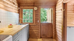 A compact kitchen with a wooden interior, a window with a view of greenery, and a sink with a faucet. - Lovely home in Højslev with kitchen (Højslev)