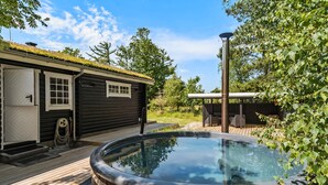 A hot tub in a backyard with a wooden deck, a small cabin, and a pergola. - Lovely home in Højslev with kitchen (Højslev)