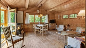 A cozy cabin with a wooden interior, a dining area, a fireplace, and a television. - Lovely home in Højslev with kitchen (Højslev)