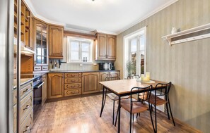 Una cocina con armarios de madera, microondas y una mesa de comedor con sillas.