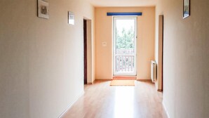 A hallway with wooden flooring, a door with a white picket fence, and a radiator on the wall. - Nice apartment in Klucze with WiFi (Klucze)