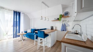 A modern kitchen with a wooden countertop, white cabinets, and blue bar stools. - 1 bedroom beach front apartment in Darlówko (Darlówko)