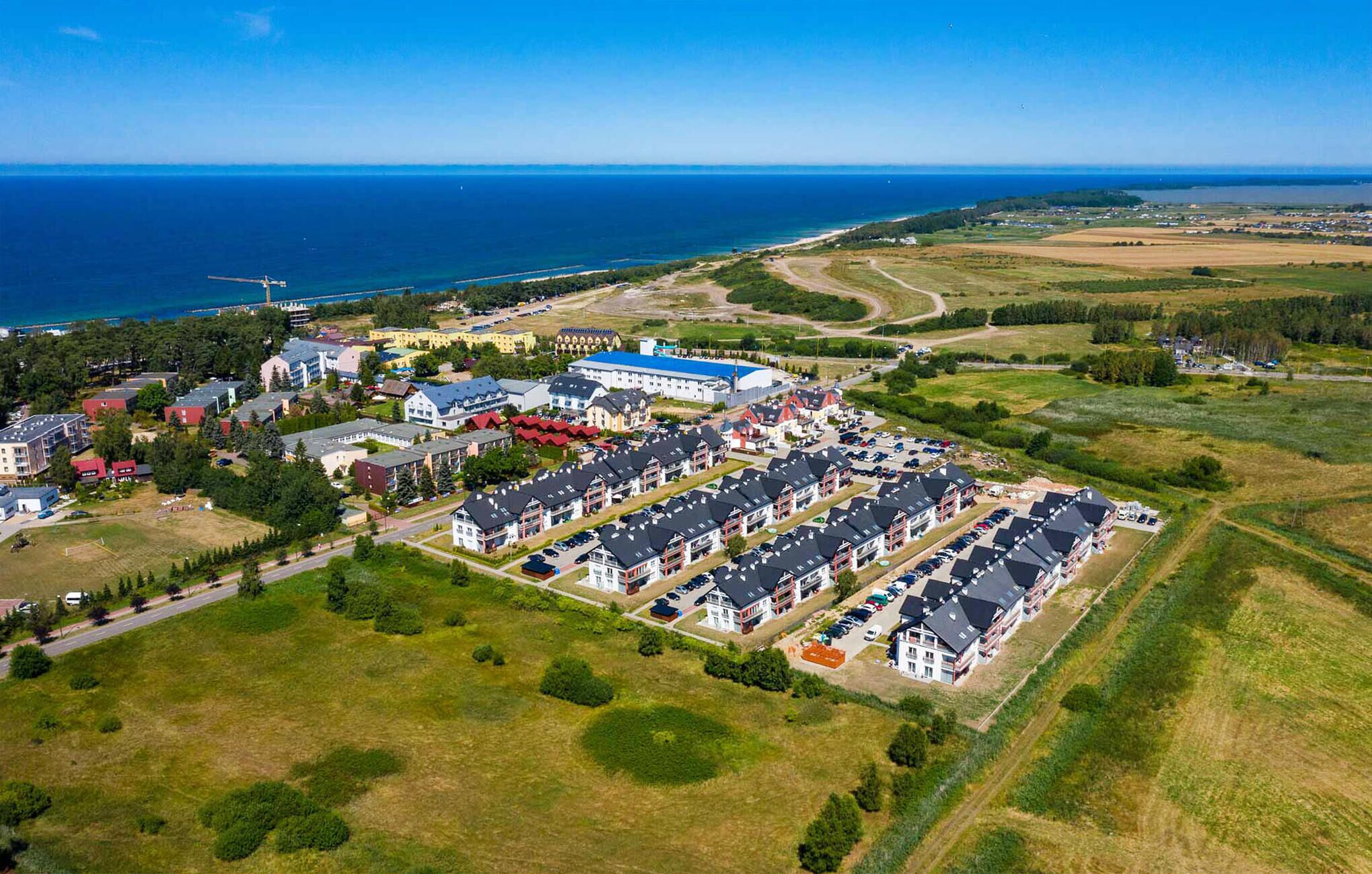 An aerial view of a residential area with multiple apartment buildings, a marina, and a large body of water in the background.