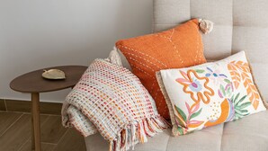 Un sofá con tres almohadones decorativos y una mesita con un adorno.