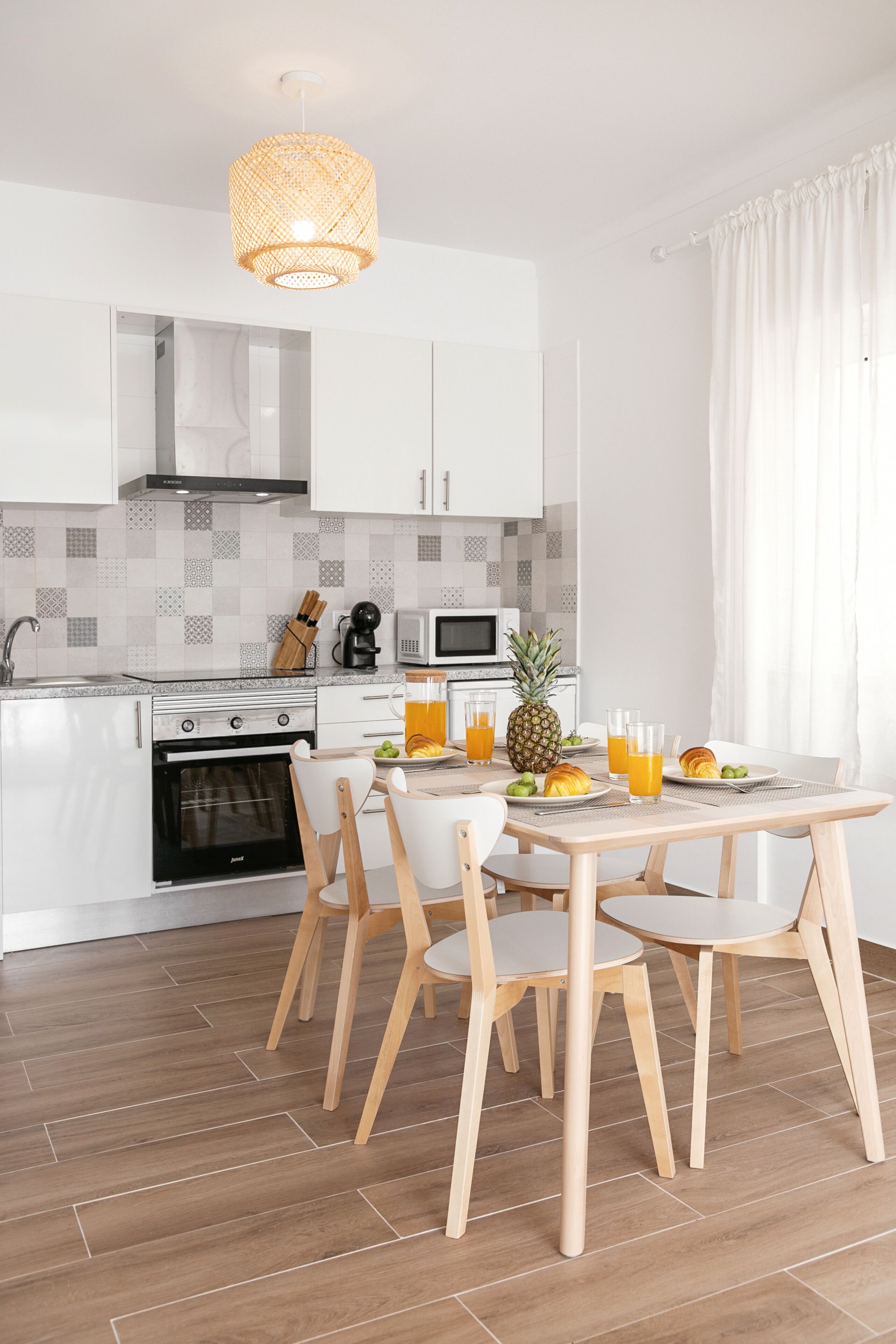 Une cuisine moderne avec des meubles blancs, un four à micro-ondes et une table à manger avec des chaises.