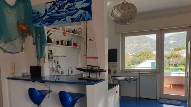 Une cuisine aux couleurs bleu et blanc, agrémentée d’une maquette de voilier et offrant une vue sur l’extérieur.