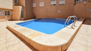 Una piscina rettangolare con bordo piastrellato, ringhiere metalliche e un galleggiante di salvataggio.
