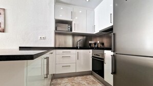 Una cucina moderna con elettrodomestici in acciaio inossidabile, mobili bianchi e un piano di lavoro nero.