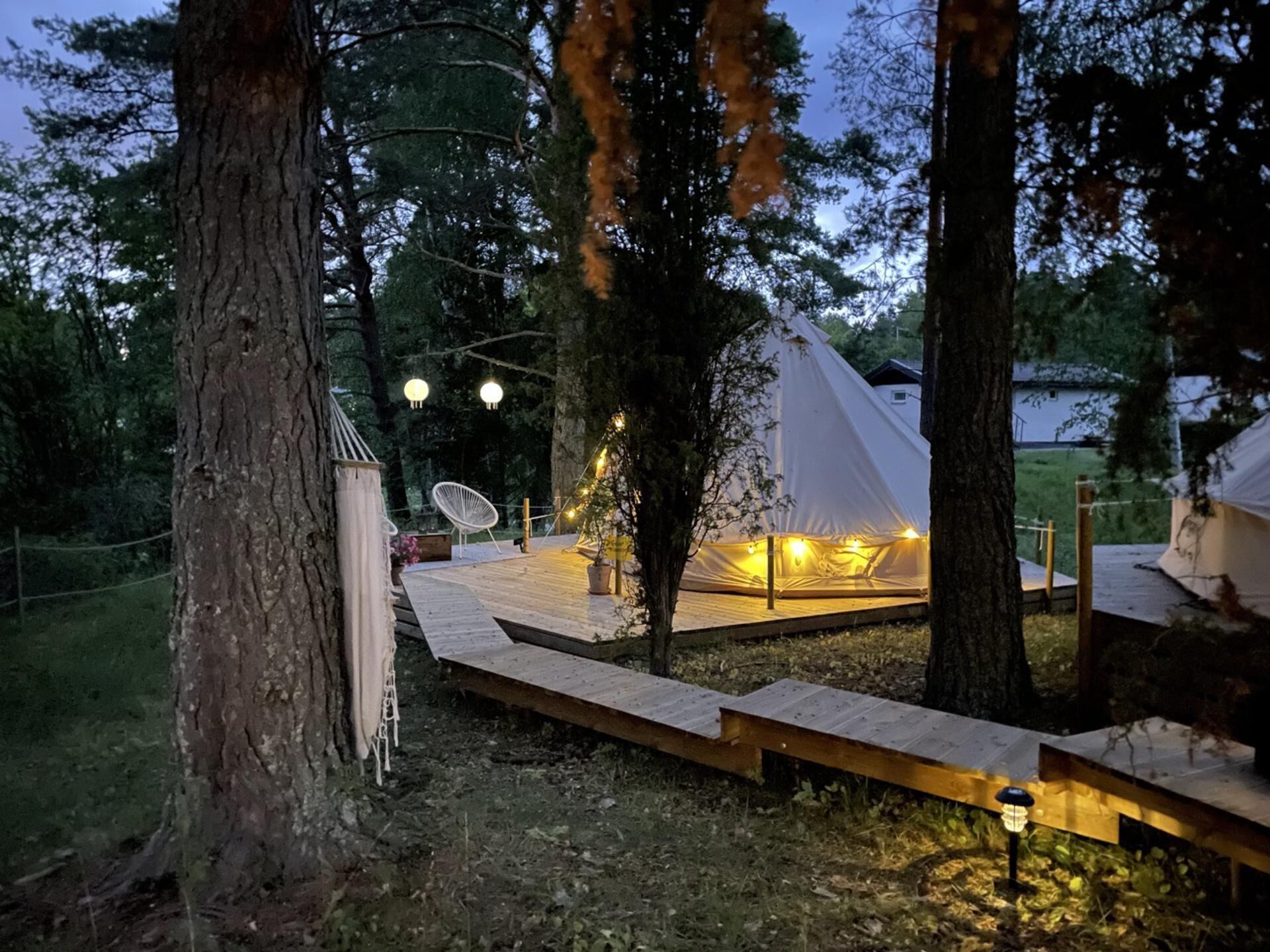 A tented outdoor area with a wooden deck, string lights, and a satellite dish.