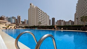 A swimming pool with metal railings, surrounded by a landscaped area with potted plants and a fence.