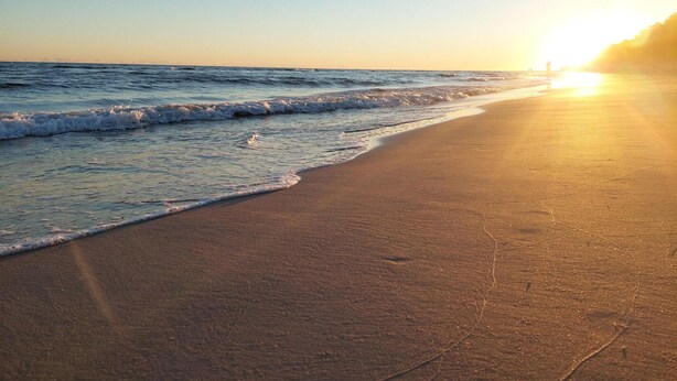 A beach with waves at sunset.