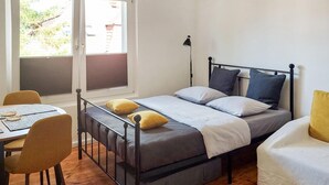 A single bed with a headboard, two pillows, a bedside table, a chair, and a lamp.