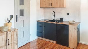 A compact kitchen with wooden cabinets, a built-in dishwasher, and a small countertop.