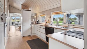 A modern kitchen with white cabinetry, a built-in dishwasher, and a large window offering a view of the outdoors. - 3 bedroom pet friendly home in Hjørring (Hjørring)