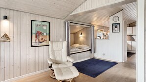 A room with a bed, a reclining chair, a blue rug, a clock, and a framed poster on the wall. - 3 bedroom pet friendly home in Hjørring (Hjørring)