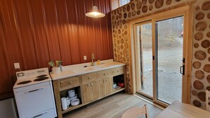 A kitchen with wooden cabinets, a white stove, and a sink. - The Forge at Torch Lake: near lake access and boat ramp, boat trailer parking (Central Lake)