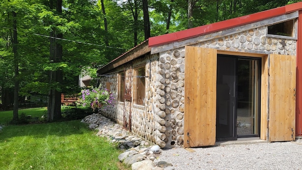 A rustic cabin with a stone exterior, wooden door, and a red roof. - The Forge at Torch Lake: near lake access and boat ramp, boat trailer parking (Central Lake)