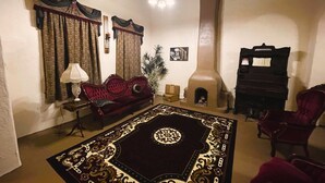 A living room with a fireplace, a sofa, a patterned rug, and a piano.