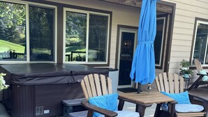 An outdoor deck with two wooden chairs and a table, a hot tub, and a blue umbrella. - Winter getaway outside of Durango-  The perfect spot between Purgatory and town! (Durango)