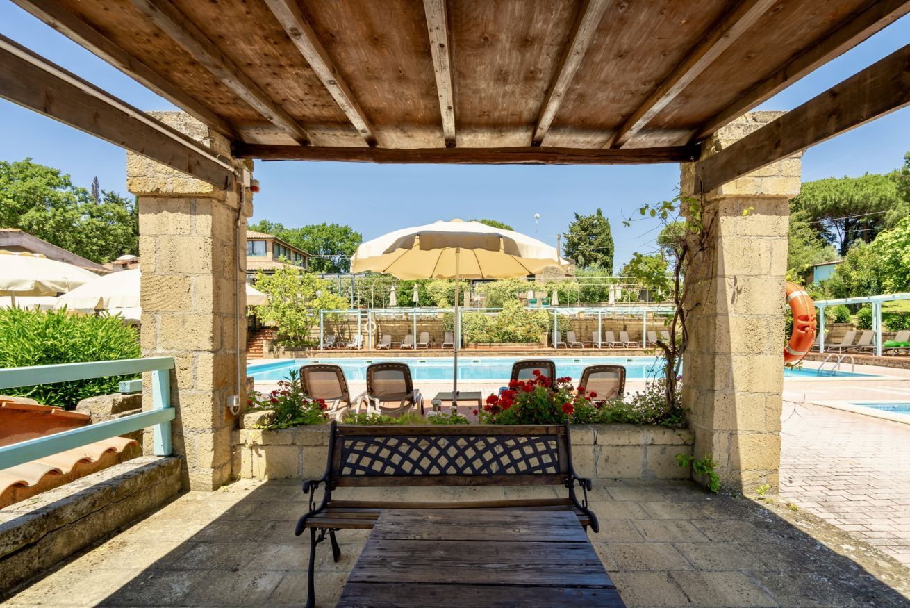 Une pergola en bois avec un banc donnant sur l’espace piscine.