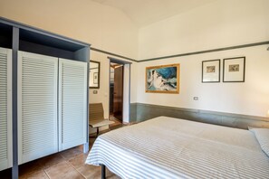 A hotel room with a bed, a wardrobe, a bench, and a painting on the wall.