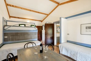 A compact room with a bunk bed, a dining table with two wine glasses, and a chair.