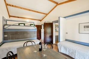 Une petite pièce comprenant un lit superposé, une table à manger avec deux verres à vin et une chaise.