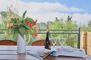 A table with a bottle of wine, two glasses, a magazine, and a vase with flowers.