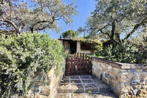 A stone staircase leading to a wooden gate, surrounded by dense foliage and trees.