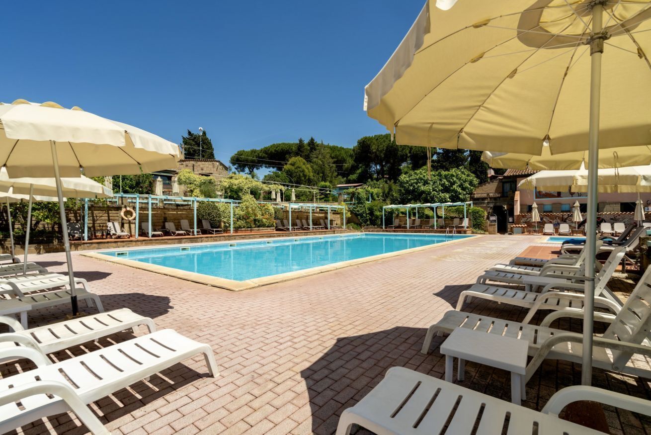 Un área de piscina con sillones de descanso y sombrillas.