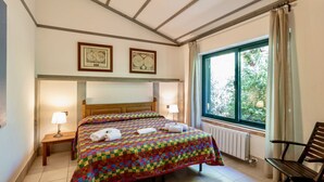 Ein Schlafzimmer mit einem großen Bett, zwei Nachttischlampen, einem Holz-Kopfteil, einem Fenster mit Vorhängen und einer Heizung.