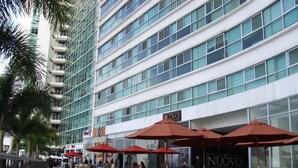 A modern hotel with outdoor seating and a prominent 'NUOVO' sign. - Departamento en Puerto Santa Ana (Guayaquil)
