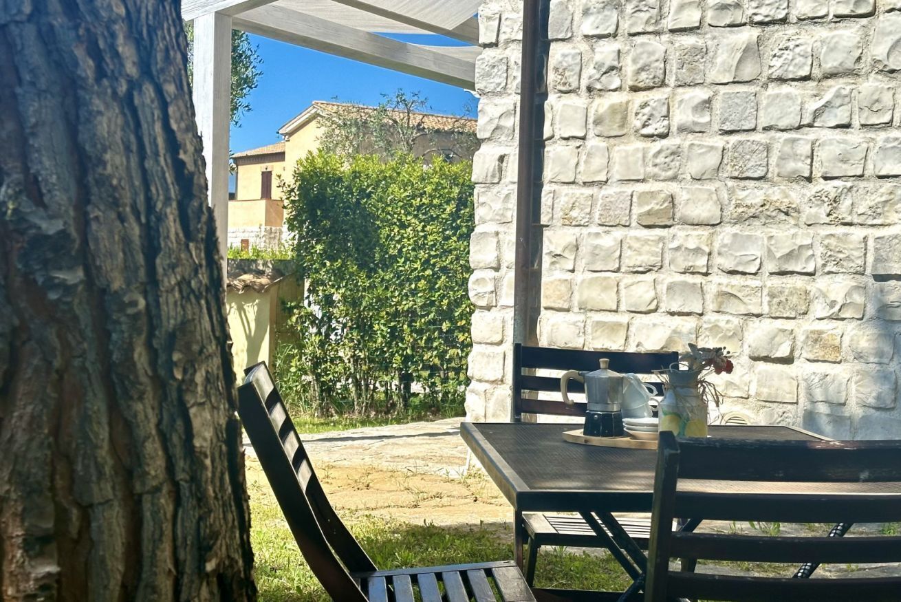 A stone wall, a table with chairs, and a tree.