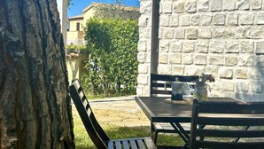 A stone wall, a table with chairs, and a tree. - M368 - Marcelli, new three-room apartment with garden (Marcelli)