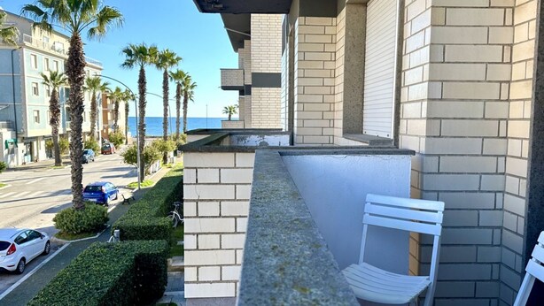 A balcony with white chairs, a view of the street, and palm trees. - P013 - Porto Recanati, renovated three-room apartment 50 meters from the sea (Porto Recanati)