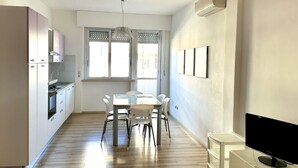 A modern kitchen with a dining table, chairs, and a TV. - P013 - Porto Recanati, renovated three-room apartment 50 meters from the sea (Porto Recanati)