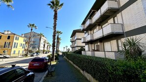 A residential street with a sidewalk, parked cars, and palm trees. - P013 - Porto Recanati, renovated three-room apartment 50 meters from the sea (Porto Recanati)