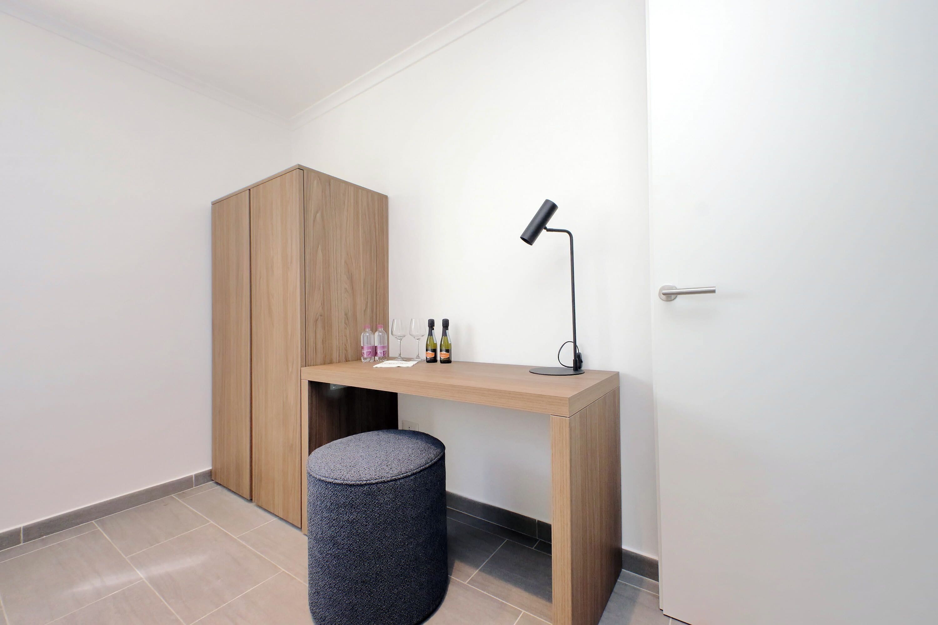 Een kamer met een houten kast, een bureau met een lamp, flessen en glazen.