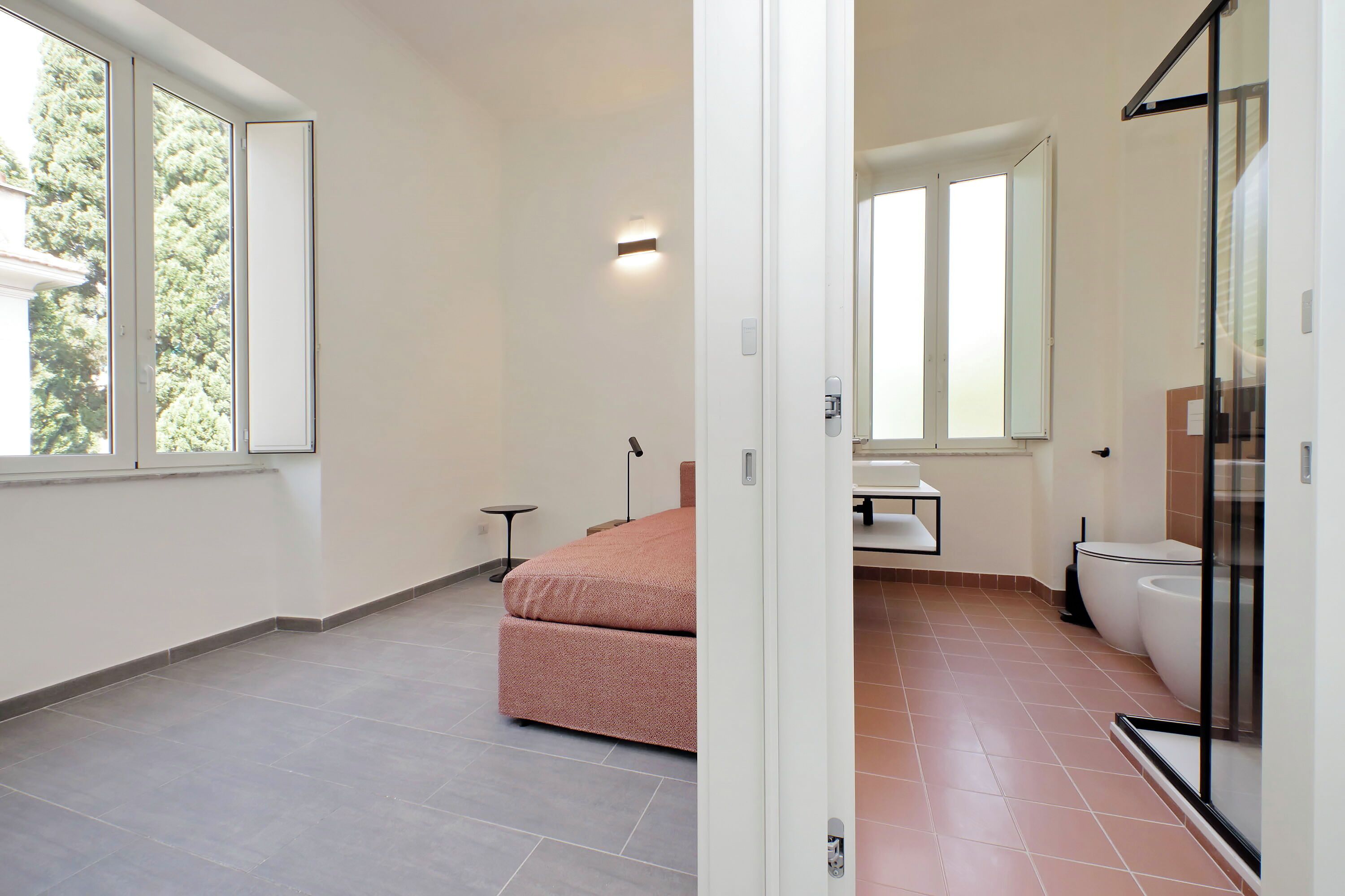 A modern bedroom with a bed, a bedside table, a nightstand, and a window.