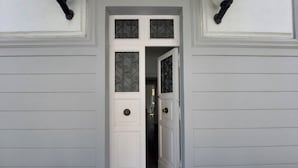 En hvid dør med en dekorativ metalgitter og en messinggreb.